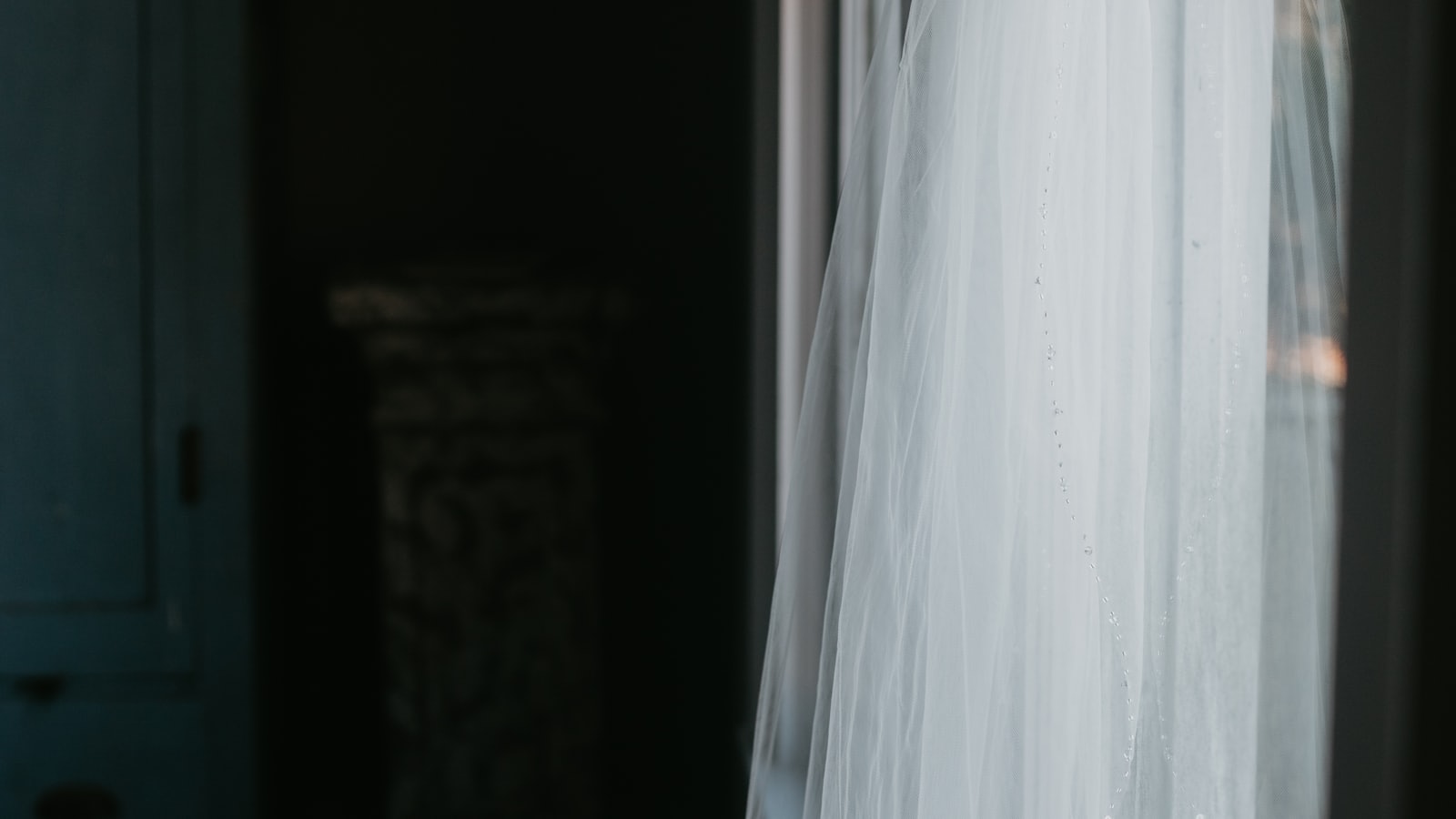 Vestido de noiva pendurado junto a uma janela